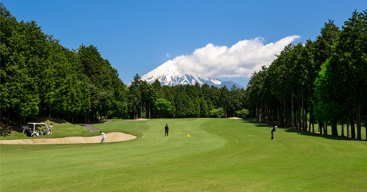 Golfers on a wide fairway at Daifuji Golf Club with Mt. Fuji beyond the treeline